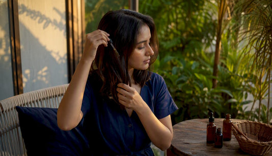 Woman applying lightweight hair oil at vanity