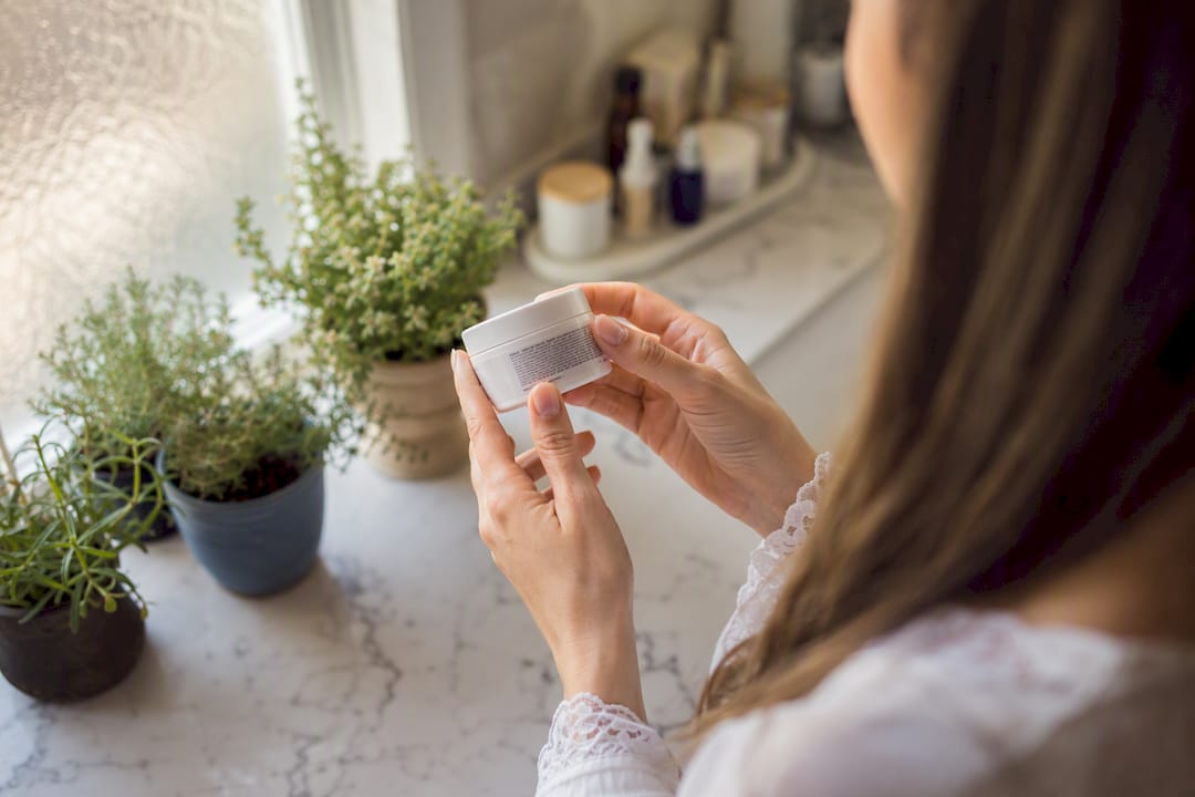 Hands reading skincare ingredient label