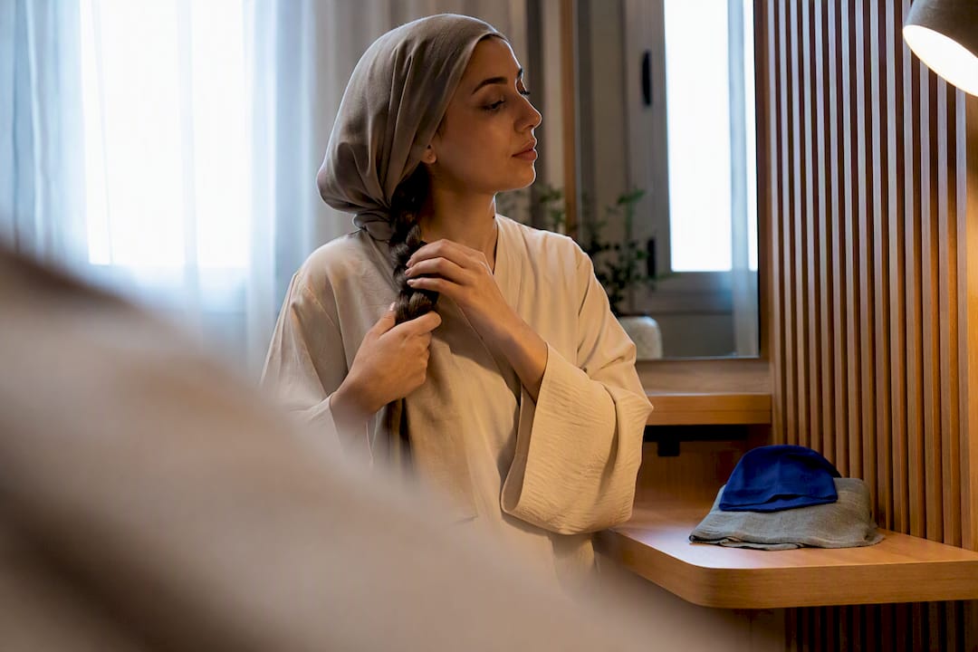 Woman preparing loose braid before wearing hijab