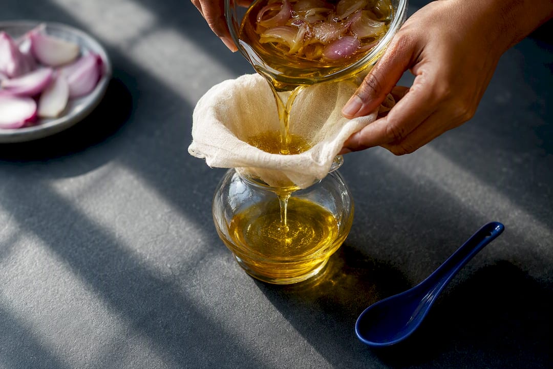 Hands straining homemade onion oil
