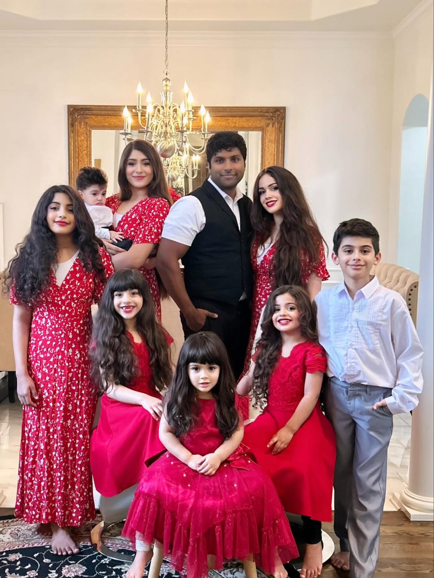 Family posing together in a decorated room with a chandelier.