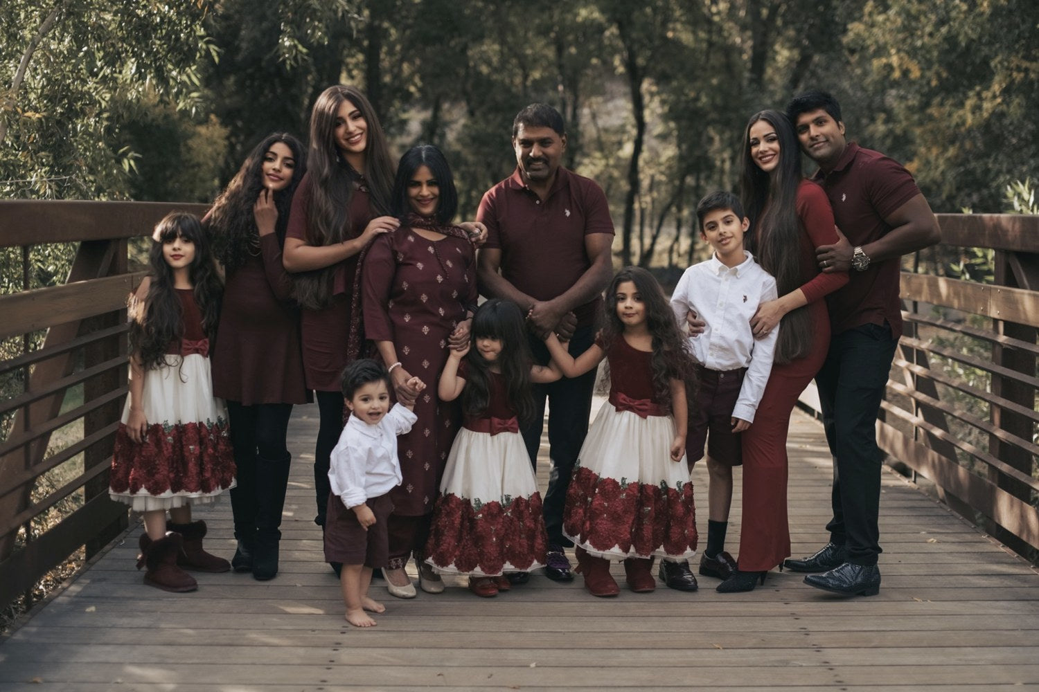 The CRISAN family together on a wooden bridge in coordinated burgundy holiday outfits